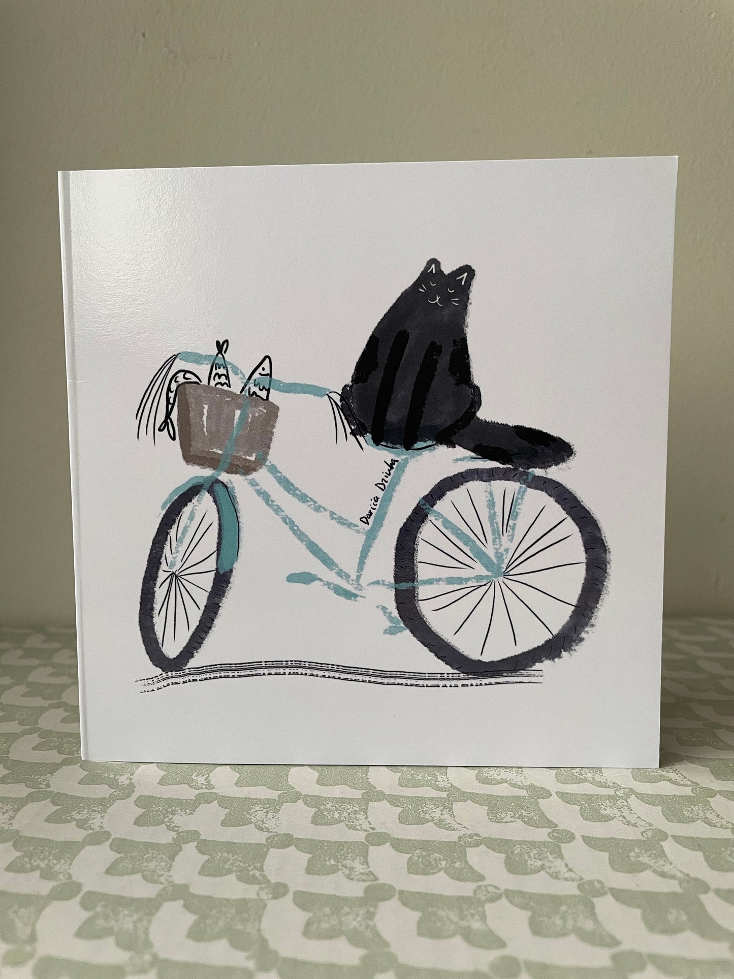 Square Greeting card: Black cat on a bicycle with fish