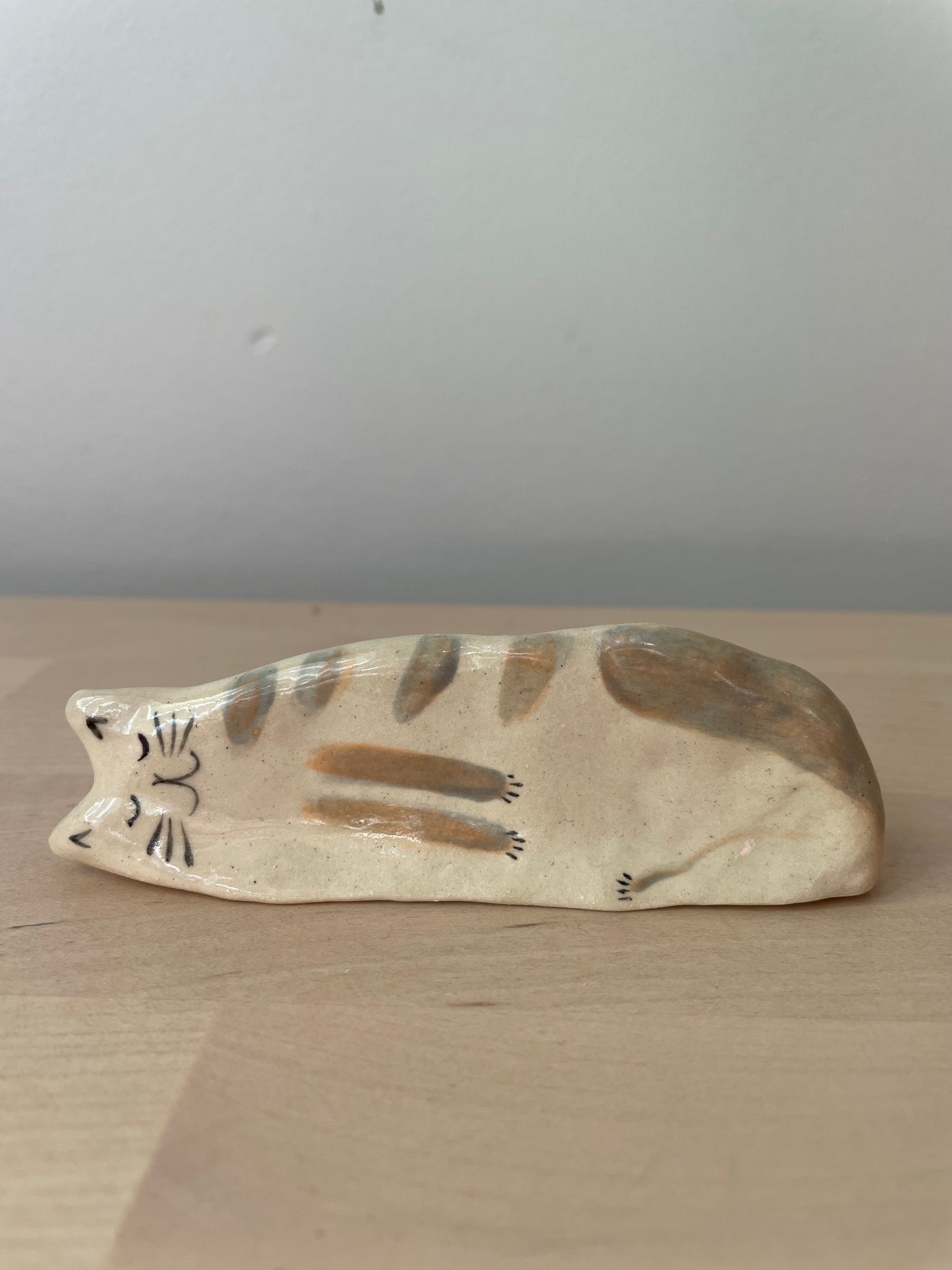 White kitty with brownish stripes lying on the side: Handmade ceramic cat figurine