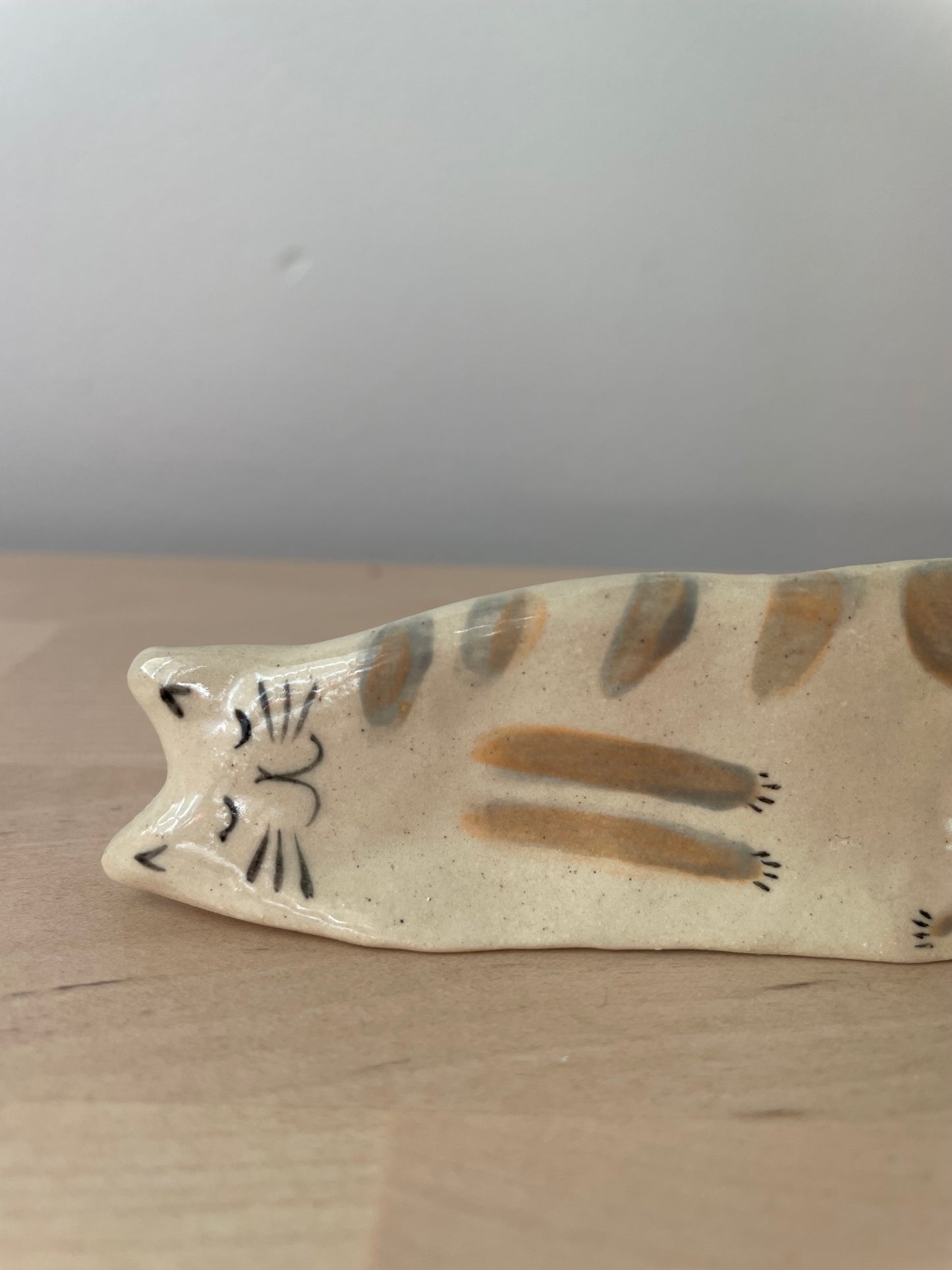 White kitty with brownish stripes lying on the side: Handmade ceramic cat figurine