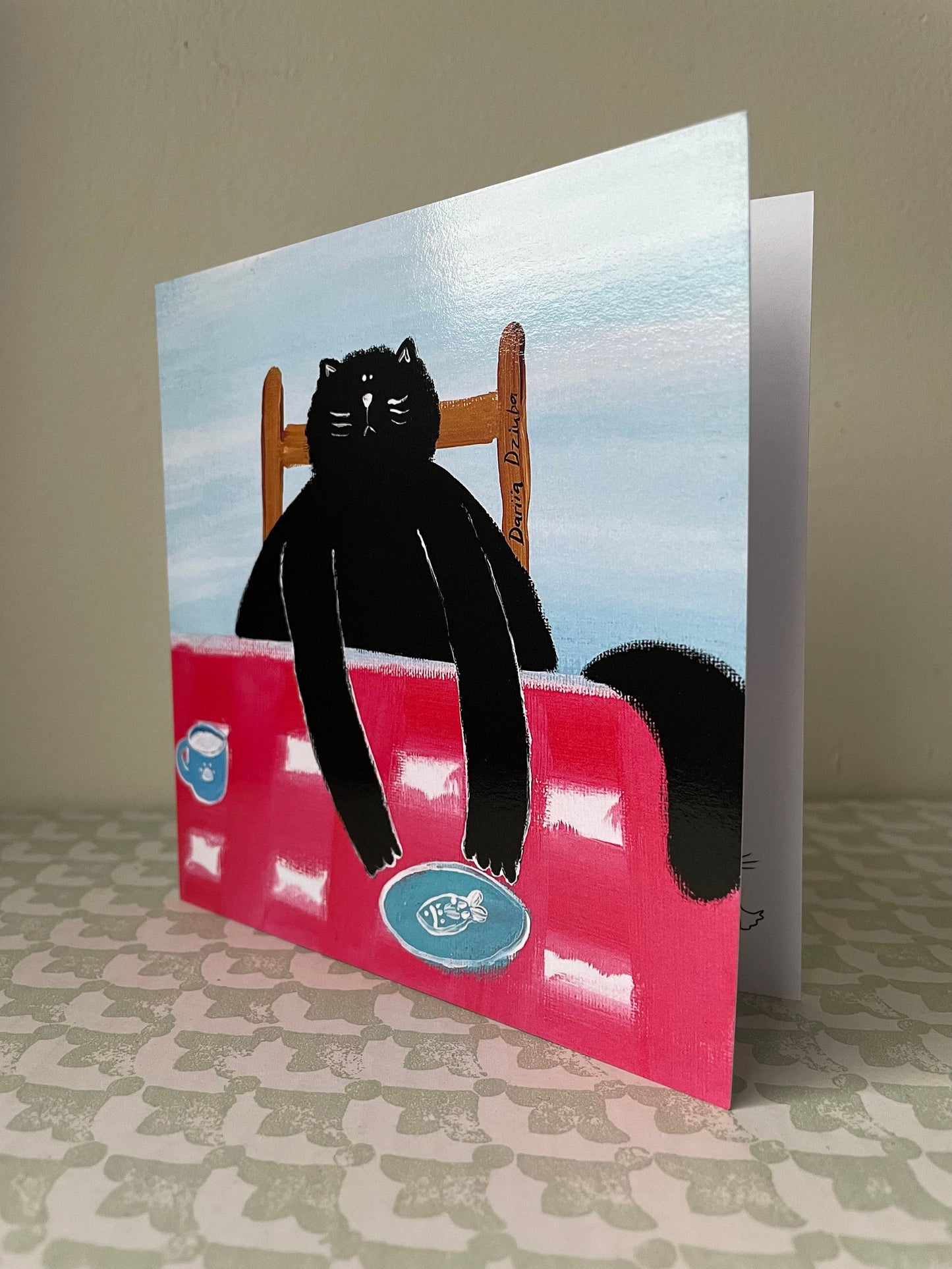 Black cat at a table: Greeting card